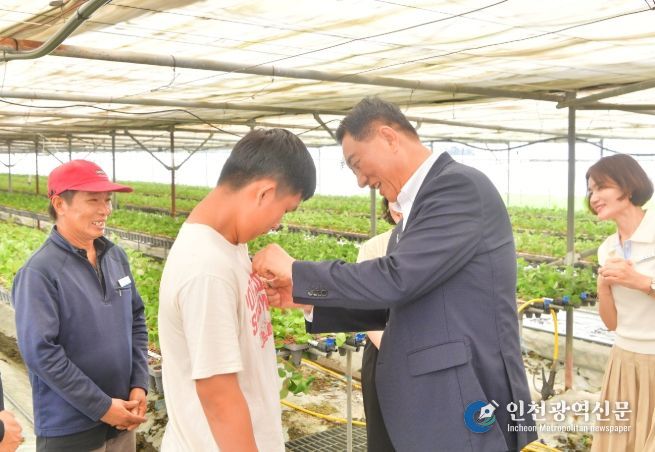 7월 김한종 장성군수가 외국인 계절근로자에게 한글 이름 명찰을 달아주고 있다.