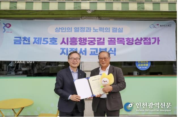 유성훈 금천구청장(왼쪽)과 김명식 상인회장이 골목형상점가 지정서 교부식을 진행하고 기념촬영을 하고 있다