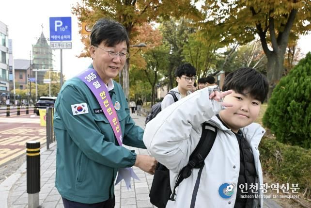 이민근 안산시장(사진 왼쪽)이 학현초등학교 앞에서 ‘스쿨존 어린이 교통안전 캠페인’을 진행하며 등교하는 어린이의 가방에 '홍이 키링'을 달아주고 있다.