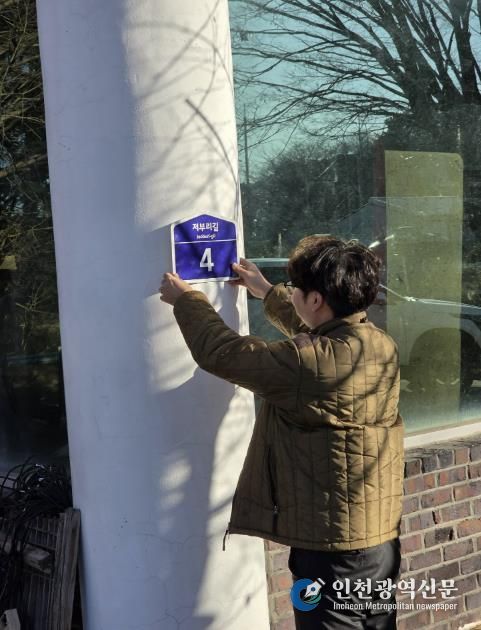 군 행복민원과 직원이 도로명주소 건물번호를 직접 배달하며 부착하고 있다.